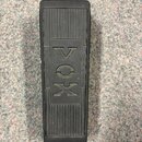 Černý sustain pedál s žebrovaným povrchem. Uprostřed je vyražen nápis VOX, který je v rámečku dopojen na text AMPLIFIER zleva a INSTRUMENT zprava. Po…