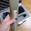 Zlatý mikrofon s mřížkou v horní části a kovovým tělem. Na boční straně je nápis -10dB a značka s čárkou. Ve spodní části jsou viditelné symboly CE,…
