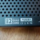 Detail spodní strany černého zařízení s perforovaným kovovým krytem. Na bílé nálepce je uveden text Apollo Twin mkII, logo UAD 2 a nápis QUAD CORE. D…