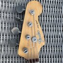 Hlava basové kytary z přírodního dřeva s nápisy Fender® a JAZZ BASS® MADE IN JAPAN. Na hlavě jsou čtyři stříbrné ladičky s kovovými knoflíky. Povrch…