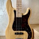 Elektrická basová kytara s přírodním dřevěným povrchem těla a hmatníkem. Nástroj má tmavě hnědý pickguard s vzorem želvy, jeden snímač a dva ovládací…