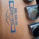 Detail zadní strany hlavy kytary z přírodního dřeva. Je zde modrý nápis RG 320 FA, sériové číslo C03017979 a text MADE IN KOREA s logem CE. Vpravo js…