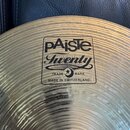 Detailní záběr na mosazný činel s viditelným rýhováním povrchu. Uprostřed je černý obdélníkový štítek s nápisy pAiste, Twenty, TRADE MARK a MADE IN S…