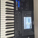 Černý digitální klavír s bílými a černými klávesami. Na levé straně je viditelné logo YAMAHA a na displeji jsou nápisy AMAN-ZIVY, Crom.Embalz, Dreams…