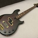 Elektrická basová kytara s tmavým, gradientním povrchem od černé po vínovou. Na hlavě hmatníku je bílý nápis YAMAHA Ltd. Nástroj má zlaté potenciomet…