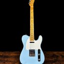 Světle modrá elektrická kytara typu Telecaster s bílým pickguardem a javorovým hnedým hmatníkem. Na hlavě je viditelné logo Fender. Nástroj vykazuje…