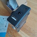 Černý kovový efekt pedál s matným povrchem. Na zadní straně jsou vidět tři konektory: USB port, kulatý napájecí vstup a USB-C port. Vedle konektorů j…