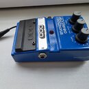 Modrý kytarový efekt s kovovým šasi. Na horní straně je bílý štítek s nápisem DOD a modrý panel s textem FX Stereo 65 Chorus a popisky SPEED, DELAY T…
