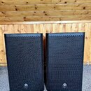 Dva černé reproduktory s kovovou mřížkou v plastovém rámu. V dolní části každého reproduktoru je umístěno kulaté logo Yamaha. Povrch mřížek vykazuje…
