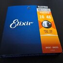 Fotografie znázorňuje balení strun pro elektrickou kytaru značky Elixir. Na modrém a oranžovém obalu jsou nápisy ELECTRIC GUITAR STRINGS, NICKEL PLAT…