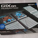 Kartonová krabice s produktem Zoom G1X on. Na povrchu je nápis „G1X on Guitar Multi-Effects Processor with Expression Pedal“ a logo „ZOOM“. V levé do…