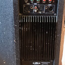 Zadní panel černého reproduktoru s nápisy kaifat a M215A. Horní část obsahuje čtyři ovládací knoflíky s popisky GAIN, GAIN, VOLUME a TREBLE, BASS, dv…