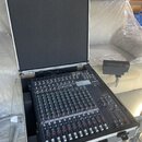 Míchací pult v hliníkovém přepravním kufru s černým polstrováním. Na přístroji je viditelné logo YAMAHA a označení modelu MG10XU. Povrch pultu je čer…