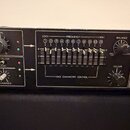 Černý rackový procesor s ovládacími prvky. Na panelu jsou knoflíky označené jako LEVEL, HARMONICS, BALANCE a VOLUME, 11 posuvníků v sekci FREQUENCY (…