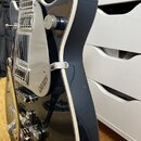Tmavě modrá elektrická kytara s bílým lemováním korpusu. Na stříbrném plechu je viditelný nápis GRETSCH ELECTRONIC. Kytara má chromované hardware a t…
