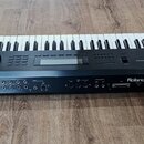 Černý digitální klavír s bílými a černými klávesami. Na zadní straně je bílý nápis Roland W-30 a štítek s textem Roland, model W-30. Zadní panel obsa…