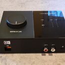 Černý audio rozhraní s velkým ovládacím knoflíkem na horní straně a nápisem OUT 1/2 VOLUME. Na horním panelu jsou viditelné kontrolky s popisky USB,…