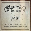Fotografie detailu štítku uvnitř akustické kytary. Na bílém podkladu je černý nápis „Martin & Co EST. 1833“, pod ním označení modelu „D-1GT“ a v doln…