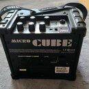 Černý kombozesilovač s rukojetí a popruhem, na kterém je nápis Roland. Na zadním panelu je velký bílý nápis MICRO CUBE, logo CE a označení N225. Jsou…