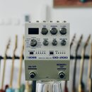 Bílý efekt pedál s nápisy BOSS DIGITAL DELAY DD-200. Horní část obsahuje displej, tři velké ovládací knoflíky s popisky TIME, FEEDBACK a E. LEVEL a t…