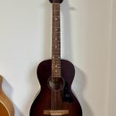 Akustická kytara s tmavě hnědým povrchem v přechodu (sunburst). Na hlavě hmatníku je bílý nápis „ArtLane“. Nástroj vykazuje čistý povrch bez viditeln…