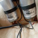 Dvě stříbrné cylindrické součástky s černým páskem. Na každé je nápis TESLA TC 682-a 8 µF ±20% MP. Součástky jsou připojené pomocí černých vodičů k p…