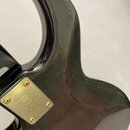 Detail zadní strany černé elektrické kytary. Na kovovém zlatavém krytu je vyryto logo Yamaha a nápis YAMAHA MADE IN JAPAN. Povrch nástroje vykazuje d…