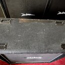 Černý kytarový kombozesilovač s povrchem z texturovaného vinylu. Horní strana je vybavena čtyřmi kovovými úchyty a vykazuje známky opotřebení v podob…