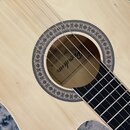 Detailní pohled na ozvukový otvor akustické kytary se světlým dřevěným povrchem. Okraj otvoru je zdoben kruhovým ornamentem s červenými a zelenými pr…