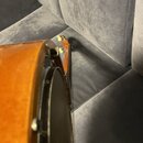Detailní pohled na bok dřevěného těla banjona v hnědé barvě. Je vidět kovový prstenec s náborem a bílé ladičky na hradle. Na nástroji nejsou žádné či…