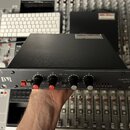 Černý rackový kompresor a limiter s kovovým předním panelem. Vlevo je logo DBR, vpravo nápis COMPRESSOR LIMITER dB. Přístroj má čtyři černé otočné kn…