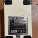 Zadní strana bílého efekt pedálu s nápisem TC HELICON a textem DESIGNED AND ENGINEERED IN CANADA. Na štítku je tabulka s instrukcemi pro FOOT SWITCH,…