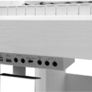 Detailní pohled na panel s konektory bílého digitálního piana. Na panelu jsou nápisy TO HOST, TO DEVICE, PHONES 1, PHONES 2, MIC, AUX IN, AUX IN / MI…