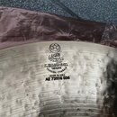 Detailní pohled na povrch kovového činele v přirozené zlatavé barvě. Na povrchu je vyryto logo hvězdy v kruhu, arabský nápis a text K.ZILDJIAN & CO.…