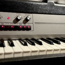 Elektronický klavír stříbrné barvy s bílými a černými klávesami. V levé horní části je nápis Wersi PIANOSTAR T 2000 a pod ním přepínač s označením St…