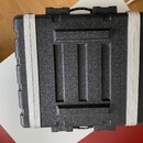 Černý tvrdý kufýr s texturovaným povrchem a hliníkovými lištami po stranách. V horní části je vidět černá plastová rukojeť. Na povrchu nejsou žádné v…