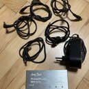 Na fotografii je stříbrný napájecí zdroj s nápisy „Harley Benton“, „PowerPlant ISO-5 Pro“ a „POWER SUPPLY“. Dole jsou uvedeny parametry: „POWER IN“,…