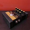 Černý efekt pedál s horním zlatým panelem a žlutými oválnými knoflíky. Na panelu je nápis BASS DRIVE BDI-2000 a logo Boss. Na horní části jsou popisk…