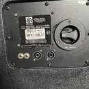Zadní strana černého reproduktorového boxu s texturovaným povrchem. Na černé kovové desce je náleplka značky Ampeg s nápisy MODEL: SVT410HLF, IMPEDAN…