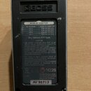Zadní strana efektového pedálu s kovovým šasi a černým plastovým krytem. Na krytu je vyražené logo BOSS a nalepený štítek s nápisem BOSS AC ADAPTOR,…