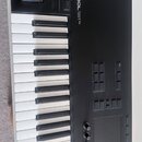 Černý MIDI kontrolér s klávesnicí. Na horním panelu je bílý nápis KONTROL S61 MK2. Nástroj obsahuje dvě velké otočné voliče, několik tlačítek a v pra…
