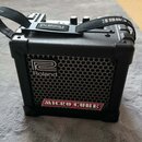 Černý kompaktní kytarový kombo zesilovač s kovovou mřížkou reproduktoru. Na mřížce je bílé logo a nápis Roland, v dolní části červený štítek s nápise…