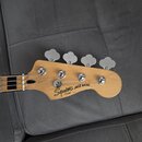 Fotografie zachycuje hlavu basové kytary z přírodního světlého dřeva s четыřmi stříbrnými ladičkami. Na dřevě je černý nápis Squier JAZZ BASS a pod n…