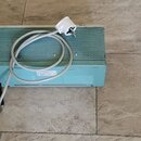 Světle modrý kombozesilovač s mřížkou reproduktoru v horní části. Na přední straně je nalepený bílý štítek s nečitelným textem a v dolní části úzký b…