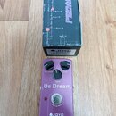 Fialový efekt pedál značky JOYO s nápisem Us Dream. Na horní straně jsou tři ovládací knoflíky označené Volume, Tone a Dist. V dolní části je spínací…