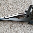 Černý bicí pedál s kovovou konstrukcí a stříbrným mechanismem. Na horní části je viditelná pružina a nastavovací šroub. Povrch pedálu vykazuje mírné…