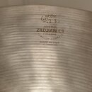 Detail kovového činchalu s viditelným koncentrickým broušením povrchu. Na nástroji je vyryté logo v arabštině a text: AVEDIS ZILDJIAN CO GENUINE TURK…