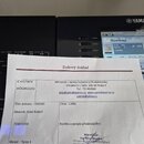 Fotografie zobrazuje daňový doklad od firmy MH servis – opravy hudební a PA elektroniky, který leží na dvou černých elektronických zařízeních. Na dok…