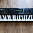 Černý klavírní syntetizátor s bílými a černými klávesami. Na levé straně horního panelu je bílý nápis Roland W-30 MUSIC WORKSTATION. V horní části se…