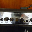 Detail ovládacího panelu kytarového komba s nápisy CLEAN a CRUNCH. Panel obsahuje vstup INPUT, čtyři otočné knoflíky s popisky VOLUME, BASS a dalšími…
